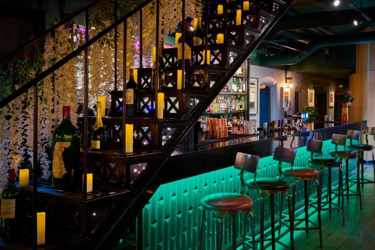 hotel bar with green chairs and wine bottles at Malmaison Oxford, Oxford Castle