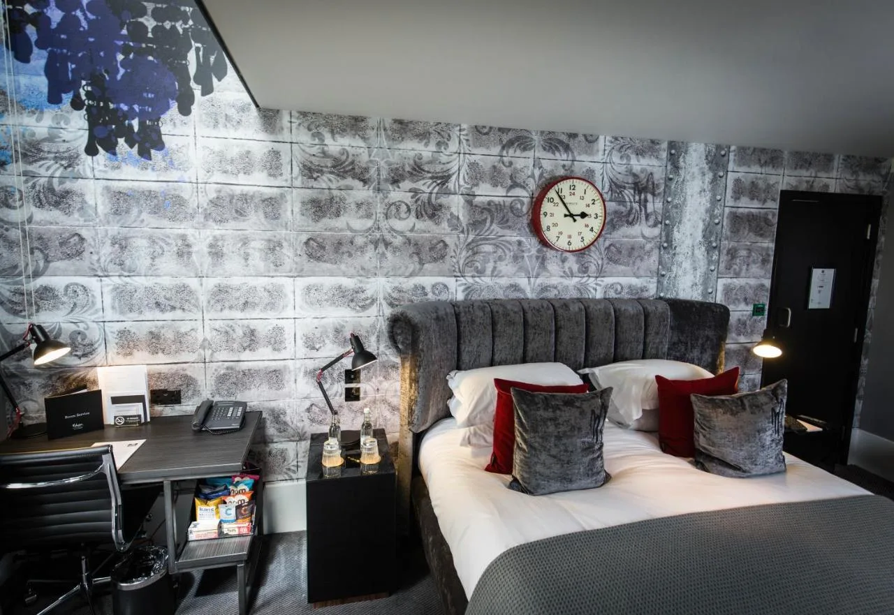 converted cell bedroom with a bed, desk and clock at Malmaison Oxford, Oxford